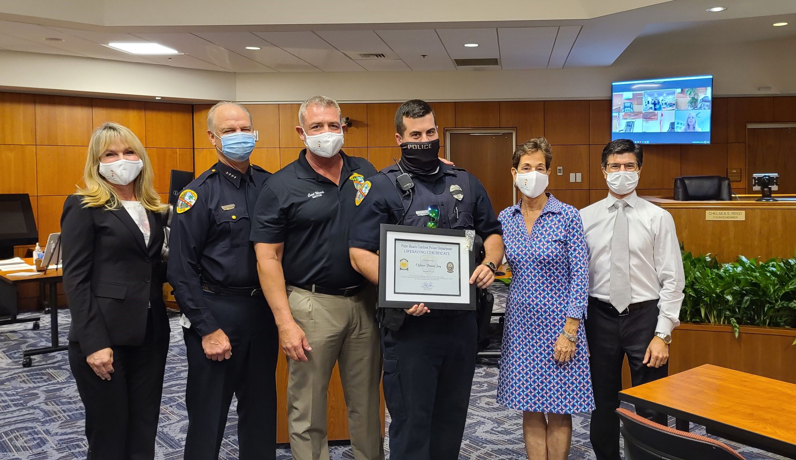 Picture of police officer, chief of police and city council holding an award. 